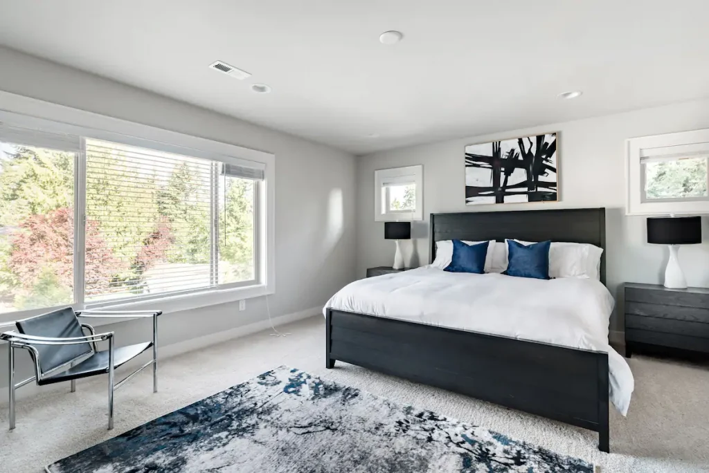 A spacious and restful room is illuminated by the natural light coming from the large window. A comfortable bed invites you to look forward to a restorative sleep this evening.