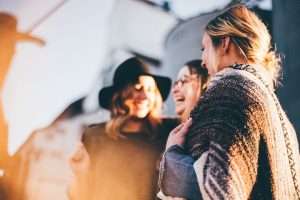 three women smile as they laugh and talk together