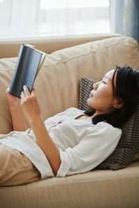 a woman lies on her back, reading a book and relaxing