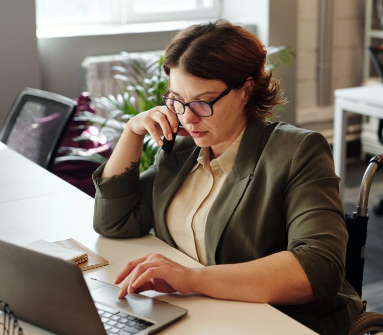 woman sits at desk working on laptop